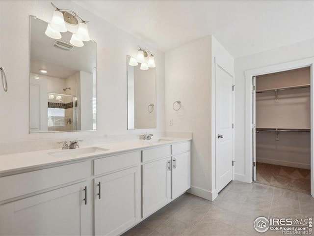 bathroom with a stall shower, double vanity, baseboards, tile patterned flooring, and a walk in closet