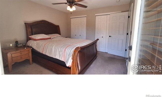 carpeted bedroom featuring multiple closets and ceiling fan