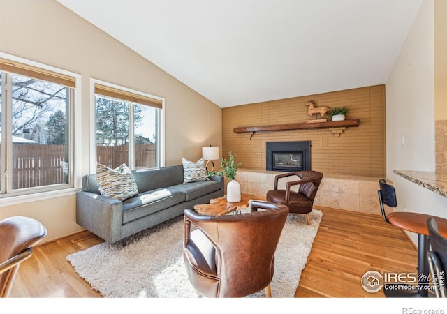 living room with a fireplace, light hardwood / wood-style floors, and vaulted ceiling