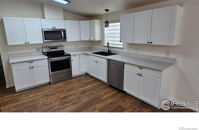 kitchen with dark wood-style floors, appliances with stainless steel finishes, white cabinets, vaulted ceiling, and a sink