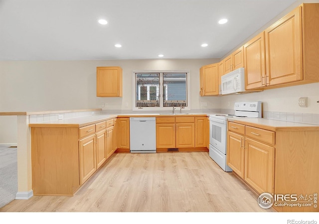 kitchen with white appliances, light brown cabinetry, sink, and light hardwood / wood-style flooring