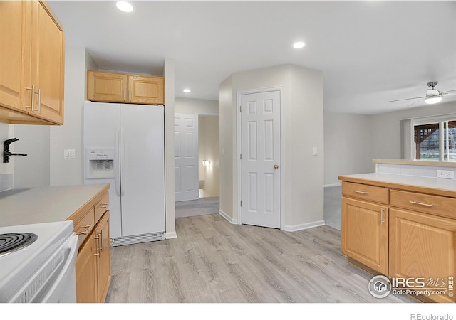 kitchen featuring ceiling fan, white fridge with ice dispenser, light brown cabinetry, and light wood-type flooring