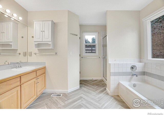 bathroom with parquet floors, vanity, and independent shower and bath
