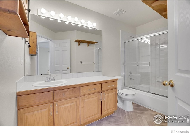 full bathroom with parquet flooring, vanity, toilet, and combined bath / shower with glass door