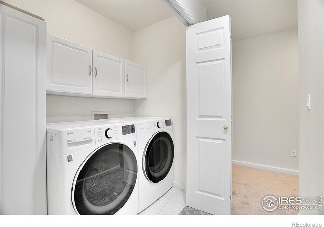 laundry area with washer and clothes dryer, light colored carpet, and cabinets