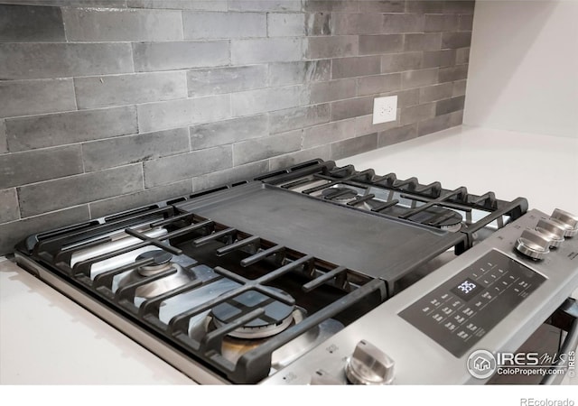 interior details featuring stainless steel gas range, cooktop, and decorative backsplash