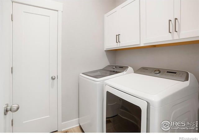 clothes washing area featuring cabinet space, baseboards, and separate washer and dryer