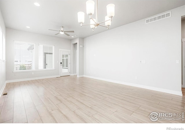 unfurnished living room featuring ceiling fan with notable chandelier, light wood-style flooring, and visible vents