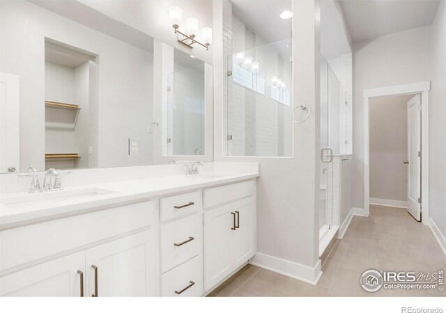 bathroom featuring a stall shower, a sink, a walk in closet, and tile patterned floors