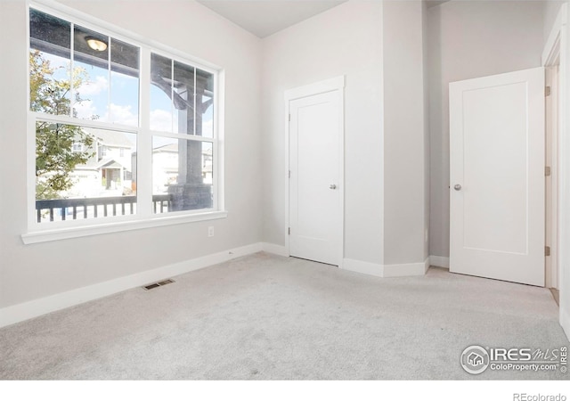 unfurnished bedroom featuring baseboards, visible vents, and light colored carpet