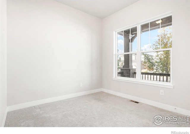 unfurnished room featuring a wealth of natural light, carpet flooring, visible vents, and baseboards