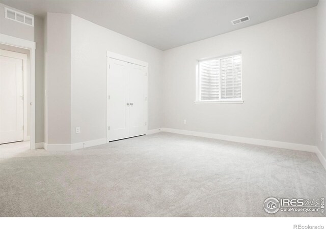 empty room with baseboards, visible vents, and light colored carpet