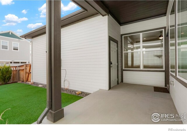 view of exterior entry with fence and a yard