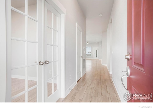 hall featuring light wood-style flooring and baseboards