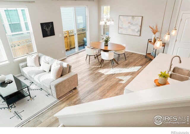 living room featuring wood-type flooring, sink, and an inviting chandelier