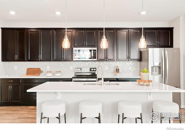 kitchen featuring stainless steel appliances, sink, a kitchen island with sink, and pendant lighting