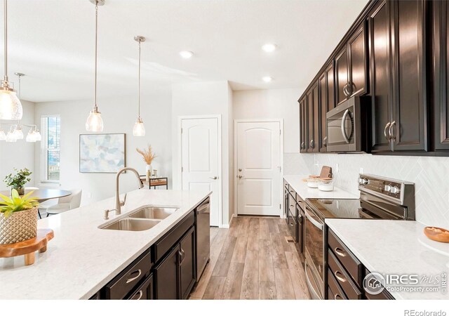 kitchen with sink, dark brown cabinets, appliances with stainless steel finishes, pendant lighting, and backsplash