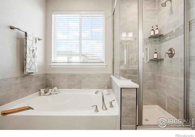 bathroom featuring plenty of natural light and separate shower and tub