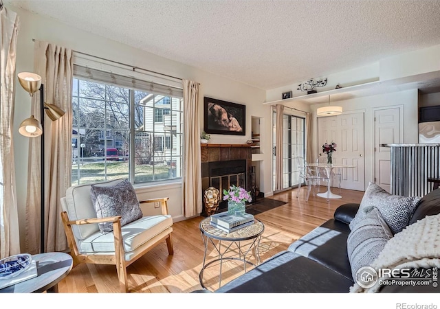 living room featuring a fireplace, a wall mounted air conditioner, wood-type flooring, and a textured ceiling