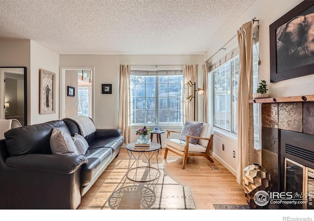 living room featuring a fireplace, light hardwood / wood-style floors, and a textured ceiling