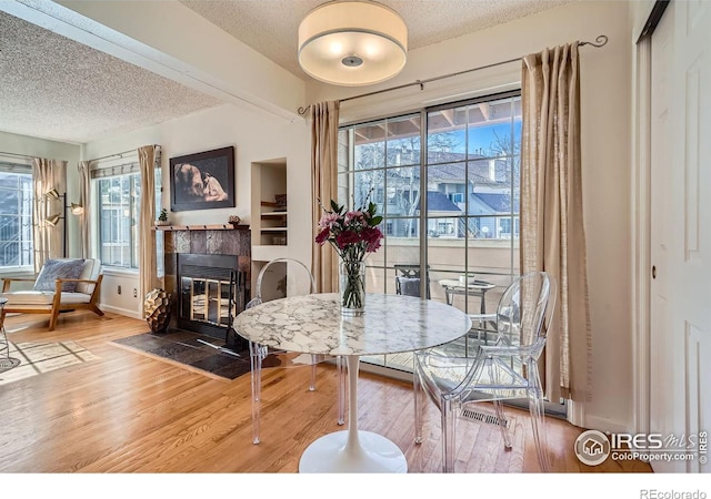 dining area featuring hardwood / wood-style floors, a fireplace, and a textured ceiling