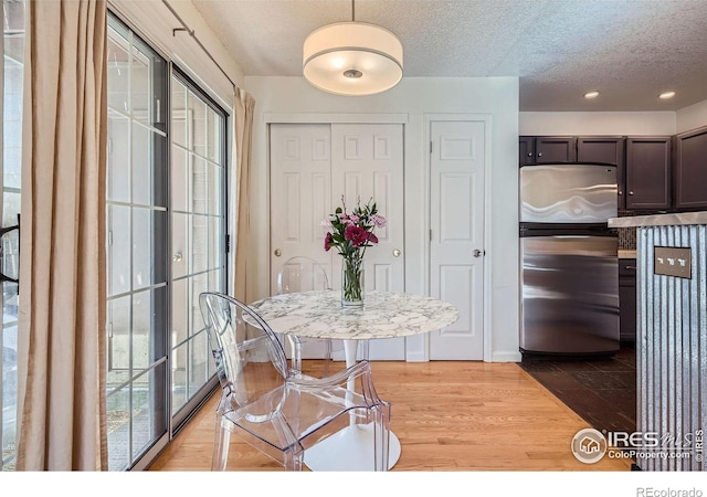 dining space featuring light hardwood / wood-style floors and a textured ceiling