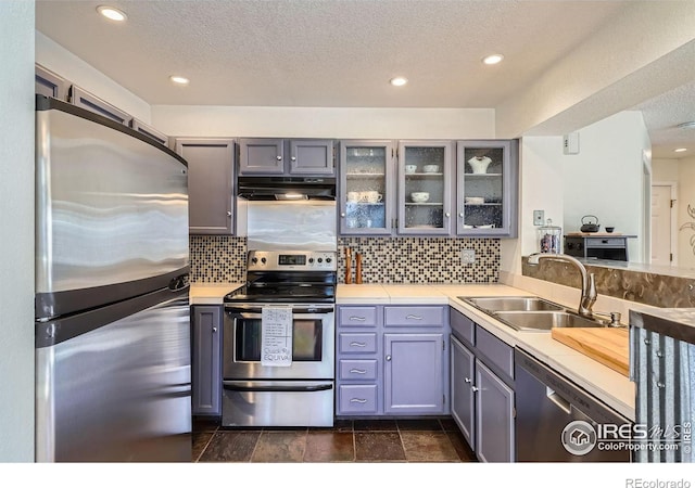 kitchen featuring appliances with stainless steel finishes, sink, gray cabinetry, and backsplash