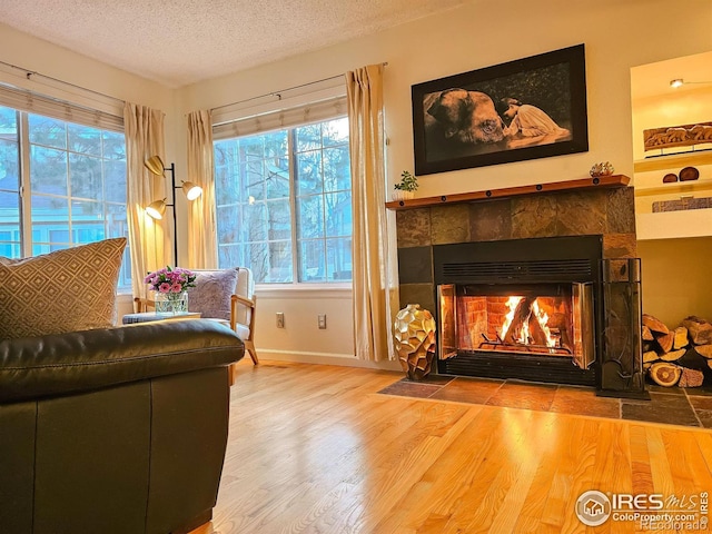 sitting room featuring wood-type flooring, a tiled fireplace, and a textured ceiling