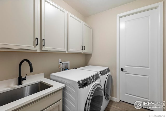 clothes washing area featuring cabinets, hardwood / wood-style flooring, sink, and independent washer and dryer