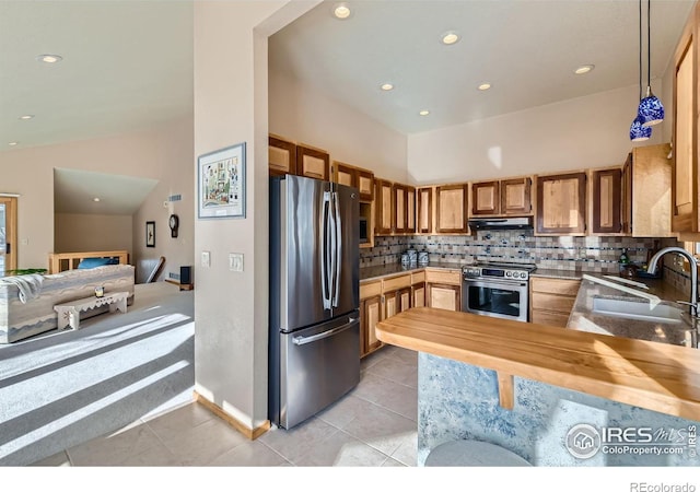 kitchen with pendant lighting, sink, appliances with stainless steel finishes, butcher block counters, and decorative backsplash