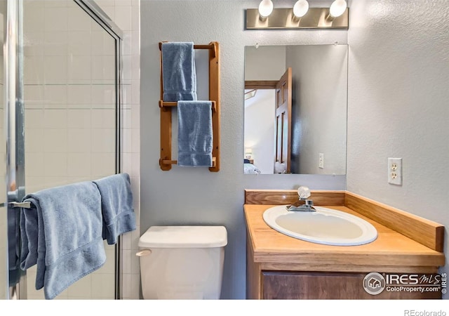 bathroom with vanity, a shower with door, and toilet