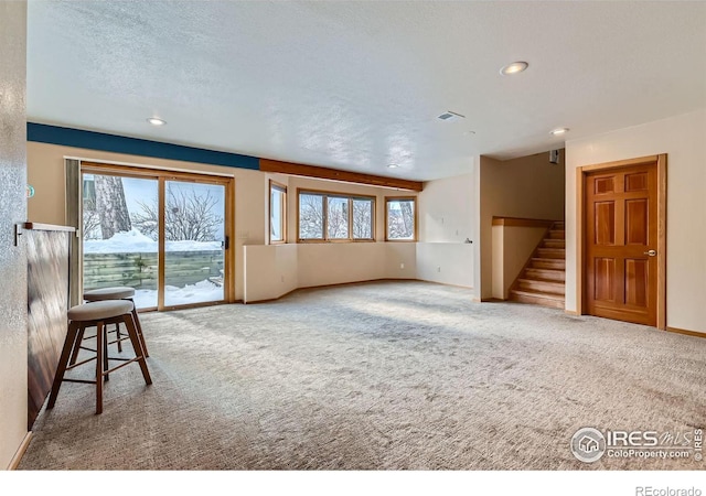 unfurnished living room featuring a textured ceiling and carpet