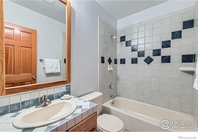 full bathroom featuring tiled shower / bath combo, vanity, decorative backsplash, and toilet