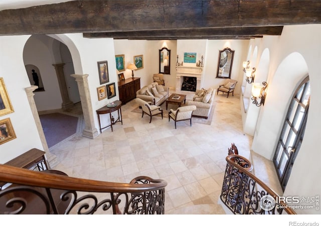 9200 Old Flowers Rd, Bellvue, CO 80512 - living room with arched walkways, beamed ceiling, a fireplace, ornate columns, and light tile patterned flooring
