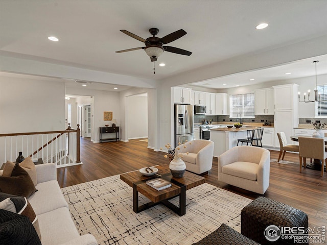 living room featuring sink, hardwood / wood-style flooring, and ceiling fan with notable chandelier