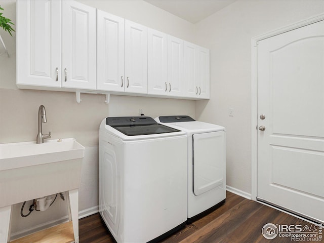 clothes washing area featuring dark wood-type flooring, cabinets, and washing machine and clothes dryer