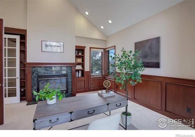 carpeted living room with a high end fireplace and high vaulted ceiling