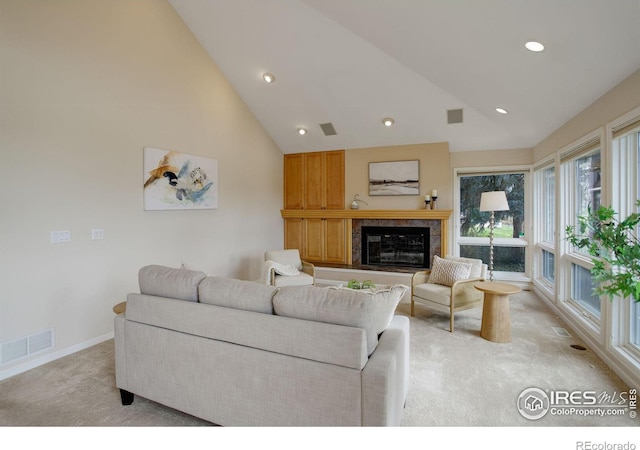 living room with high vaulted ceiling, a tile fireplace, and light carpet