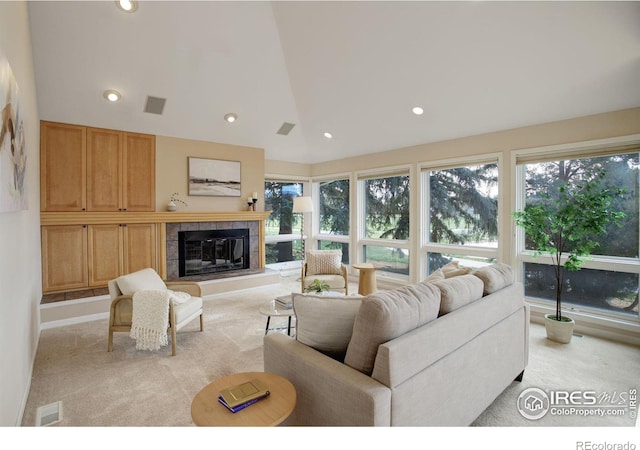 carpeted living room with vaulted ceiling and a tile fireplace