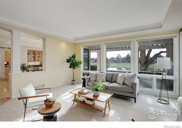 living room with crown molding, a raised ceiling, and decorative columns