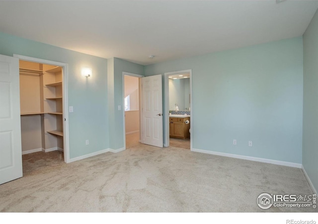 unfurnished bedroom with a closet, connected bathroom, a spacious closet, and light carpet