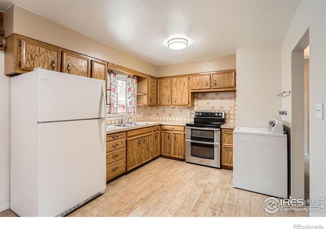 kitchen with sink, separate washer and dryer, white refrigerator, double oven range, and light hardwood / wood-style floors