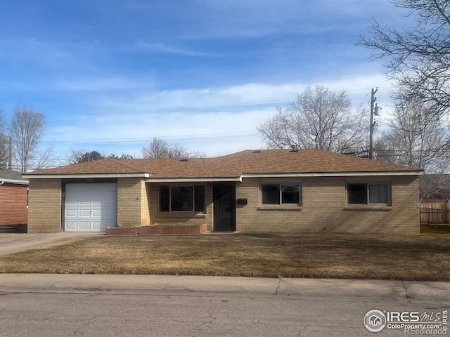 ranch-style home featuring a front lawn, brick siding, an attached garage, and a shingled roof