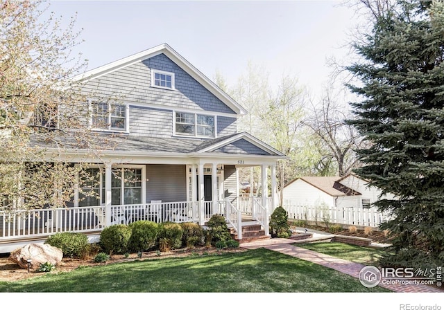 view of front of home with a front lawn, covered porch, and fence
