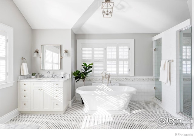 bathroom with a shower stall, tile patterned flooring, vanity, baseboards, and a freestanding tub
