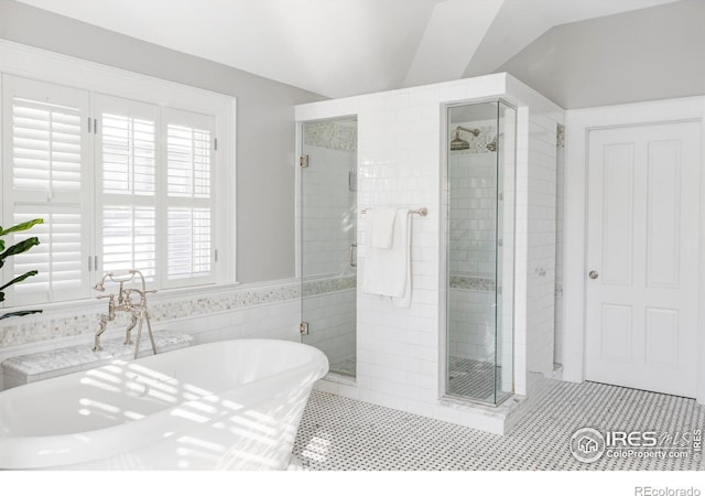 bathroom featuring a shower stall, a soaking tub, lofted ceiling, and tile patterned flooring