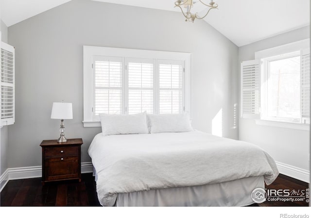 bedroom with dark wood-style flooring, vaulted ceiling, baseboards, an inviting chandelier, and multiple windows