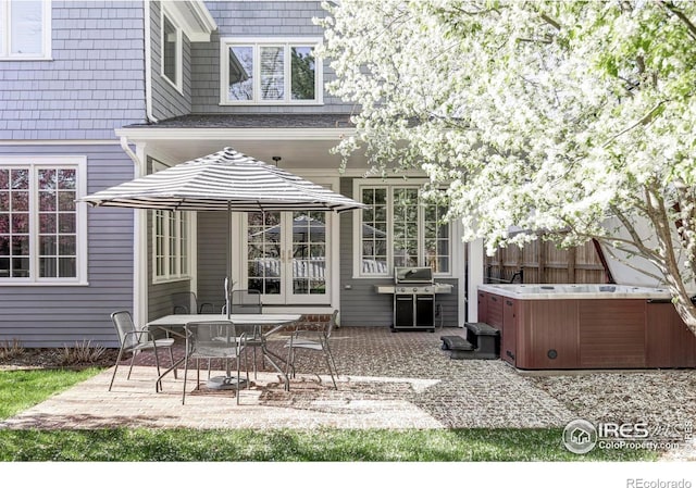 back of house with fence, a hot tub, and a patio area