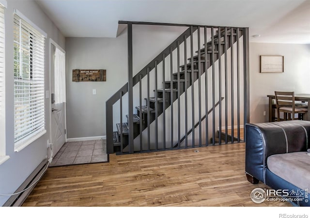 foyer entrance with baseboard heating and wood-type flooring