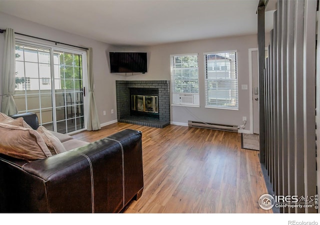 living room featuring hardwood / wood-style floors, a brick fireplace, and a baseboard heating unit